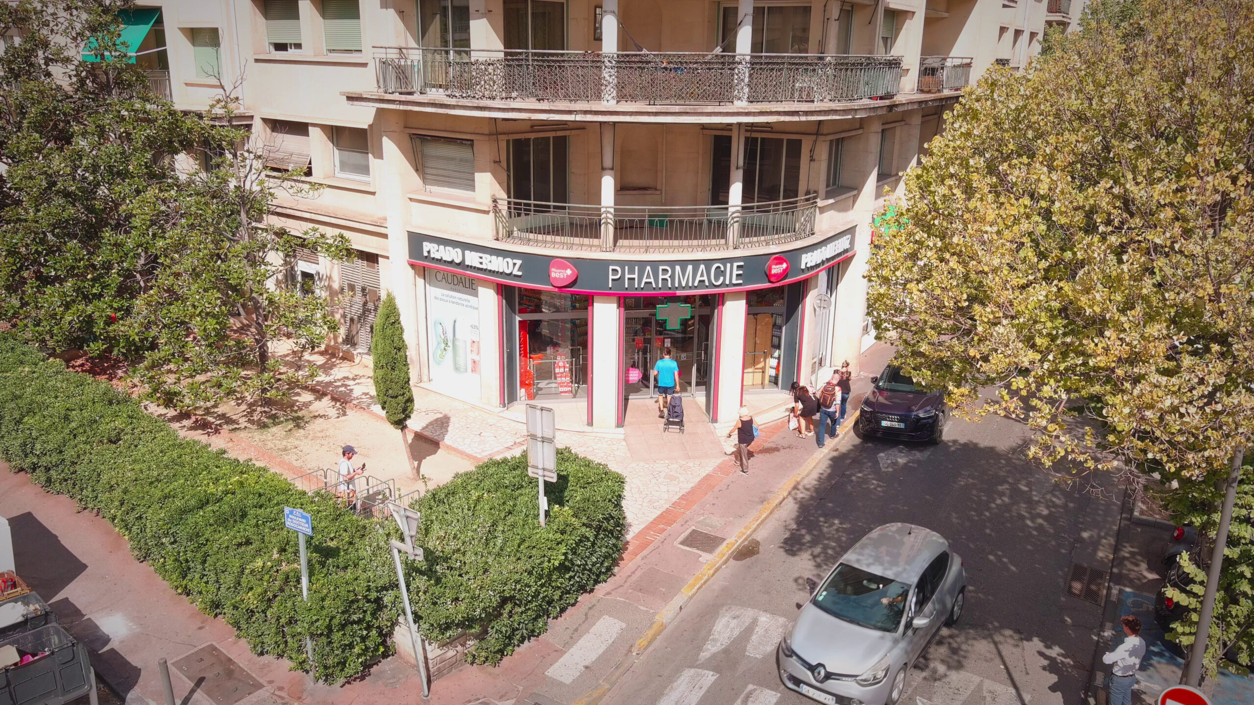 Corner facade of Pharmacie Prado Mermoz with customers on the terrace and view onto street